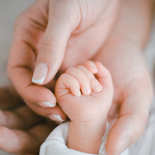 Close-up of adult hands holding a baby's foot